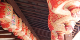 破旧建筑上的纸灯笼。在东方国家阳光明媚的日子里，红纸灯笼悬挂在风化的混凝土庙宇建筑的天花板上。传统的装饰