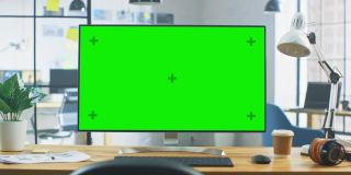 在现代创意办公室的桌子上站立的绿色宽模型桌面电脑。在背景明亮的创意Loft为开发商和设计师的专业工作