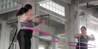 一个超重的年轻女子正在用呼啦圈锻炼