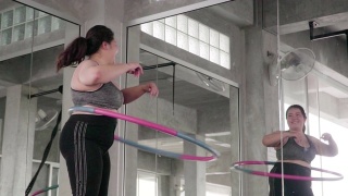一个超重的年轻女子正在用呼啦圈锻炼视频素材模板下载
