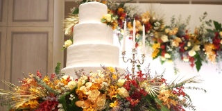 在婚礼上，白色的婚礼蛋糕上装饰着彩色的鲜花和白色的蜡烛。