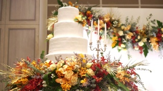 在婚礼上，白色的婚礼蛋糕上装饰着彩色的鲜花和白色的蜡烛。视频素材模板下载