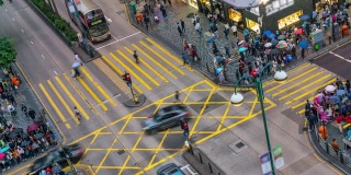 在中国香港尖沙咀区，人们和出租车穿过一个非常繁忙的十字路口
