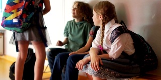 课间休息时，同学们坐在走廊的长凳上聊天。一个十几岁的女孩向她的朋友打招呼