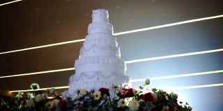 在明亮的灯光背景下，用鲜花装饰的白色婚礼蛋糕。