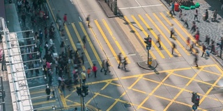 在中国香港尖沙咀地区，人们和出租车穿过一个非常繁忙的十字路口