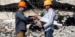 工程师们在拆除建筑物时握手。结构工程师与承包商就雇佣价格达成一致并计算建筑和维修房地产成本后达成的协议。