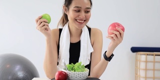 美丽的亚洲女人健康的博主展示了苹果水果和干净的减肥食品。在摄像机前录制在家的视频直播。在线社交媒体上的健身影响者。