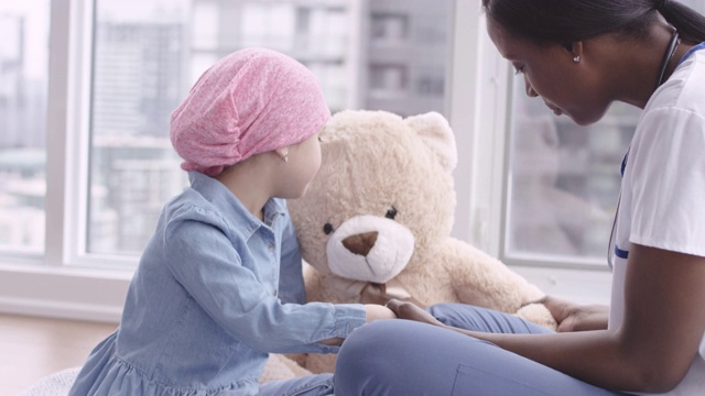 女医生坐在儿童病人与癌症斗争