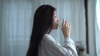 面部表情由年轻女子在纯净的早晨时间，喝牛奶视频素材模板下载