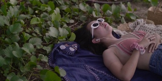 亚洲性感女孩在比基尼躺在沙滩上享受插入耳机。