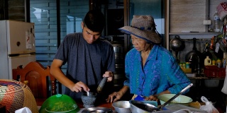 亚洲老年妇女和孙子在厨房做饭。