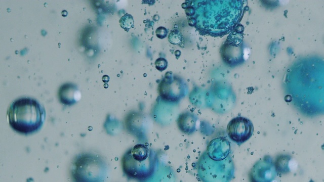 用显微镜对液体中蓝色微粒分子的慢镜头宏观分析，用于护肤美容化妆品的科学实验室研究