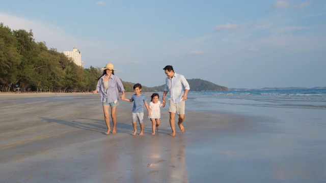 亚洲家庭愉快的散步，放松和休息在海滩夏季一起度假。家庭、旅游、暑期度假的概念。4 k决议。