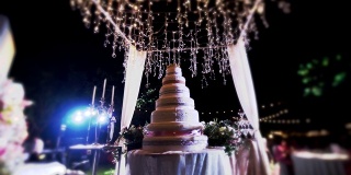 优雅的白色婚礼蛋糕在户外聚会的夜晚。
