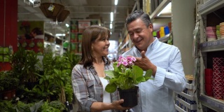 一对快乐的成熟夫妇在一家家装店买了一株植物，看起来很满意，面带微笑