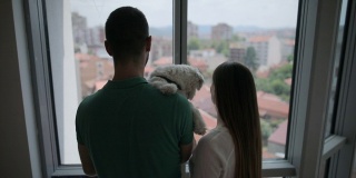 一对年轻夫妇和他们的狗在他们新家的阳台上做白日梦