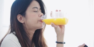 微笑的女人喝着橙汁