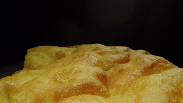 微距幻灯片拍摄的一片佛卡夏面包在黑色的背景。