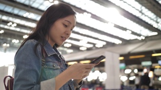 亚洲女性在机场使用智能手机视频素材模板下载