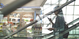 一名女子在机场的自动扶梯上使用智能手机