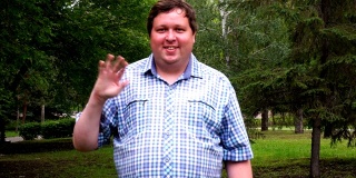 一个穿着格子衬衫的胖子在公园里开心地用手敬礼