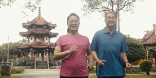 两个活跃的亚洲老人在公园里动力行走(慢镜头)