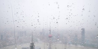 夏天的雨点落在窗户玻璃上，超级慢镜头，以上海外滩地标为背景的暴雨。