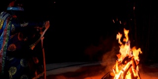 一个萨满坐在火边的剪影。