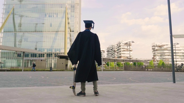 一名大学生刚毕业，穿着毕业生长袍玩滑板，在市中心的高楼大厦之间表演特技。