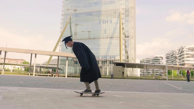 一名大学生刚毕业，穿着毕业生长袍玩滑板，在市中心的高楼大厦之间表演特技。