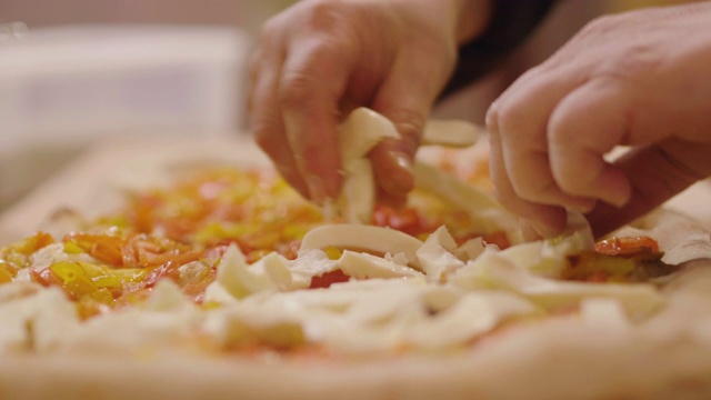 近距离的一个披萨厨师的手填高质量的意大利美食成分的披萨