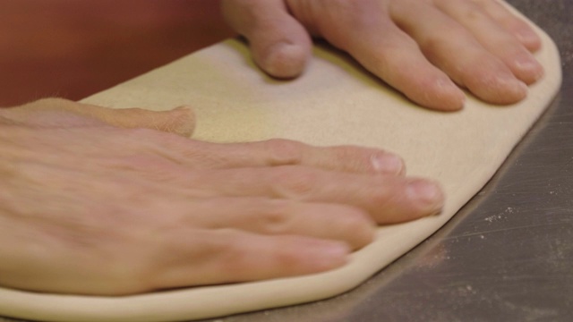 近距离的一个披萨厨师的手填高质量的意大利美食成分的披萨。