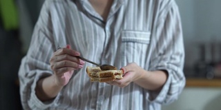 面部表情由年轻女子在纯净的早晨时间，烹饪和吃三明治