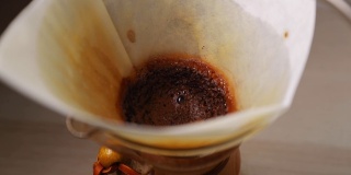 在往咖啡壶里浇水时，可以看到玻璃罐里的白色滤水器，用来滴咖啡，将水倒在咖啡上，滤水器周围以每秒120帧的慢动作捕捉。