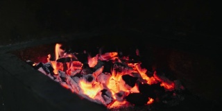 美丽的红火由切片的木头，深灰色的黑色煤内的金属火盆。木头在火盆里燃烧着明亮的黄色火焰。火苗为烧烤做饭做准备。火盆烧烤4k