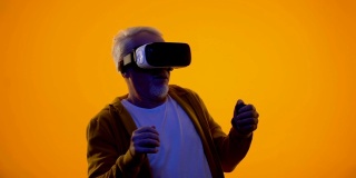 男性退休老人戴着虚拟现实眼镜玩电子游戏，现代科技