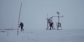 两个人在暴风雪中站在山顶上。