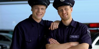 两个穿着警服戴着帽子的大副微笑着，看着摄像机，实习生