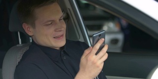 年轻的警察坐在警车里用智能手机在社交网络上聊天