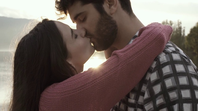 一对浪漫的年轻情侣在湖边相遇并亲吻