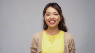 微笑的年轻亚洲女人的肖像在开襟羊毛衫视频素材模板下载