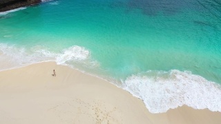 鸟瞰图的女人走在努沙佩尼达风景优美的海滩上视频素材模板下载