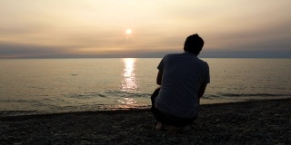 日落时分，一名男子在伊利湖上跳石头