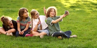 同学们在公园里自拍。四名小学生和青少年用智能手机拍照。学校友谊，学校节日快乐