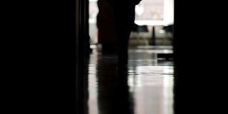 闭锁背光拍摄的一个不认识的女人在高跟鞋走下办公室走廊的慢动作，低角度的特写
