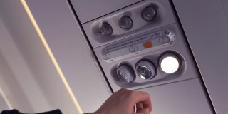 乘客的手打开飞机上的灯。特写镜头。