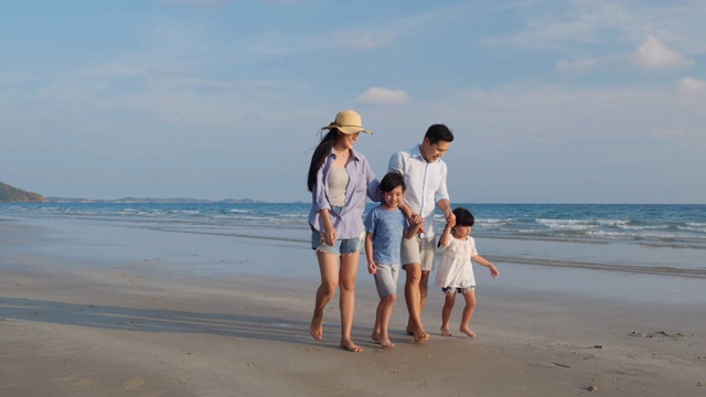 亚洲家庭愉快的散步，放松和休息在海滩夏季一起度假。家庭、旅游、暑期度假的概念。4 k决议。