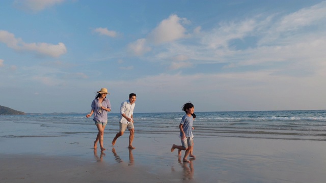 亚洲家庭愉快的散步，放松和休息在海滩夏季一起度假。家庭、旅游、暑期度假的概念。4 k决议。