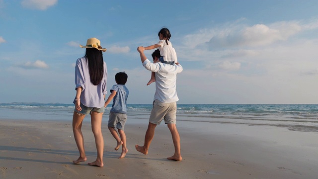 亚洲家庭愉快的散步，放松和休息在海滩夏季一起度假。家庭、旅游、暑期度假的概念。4 k决议。